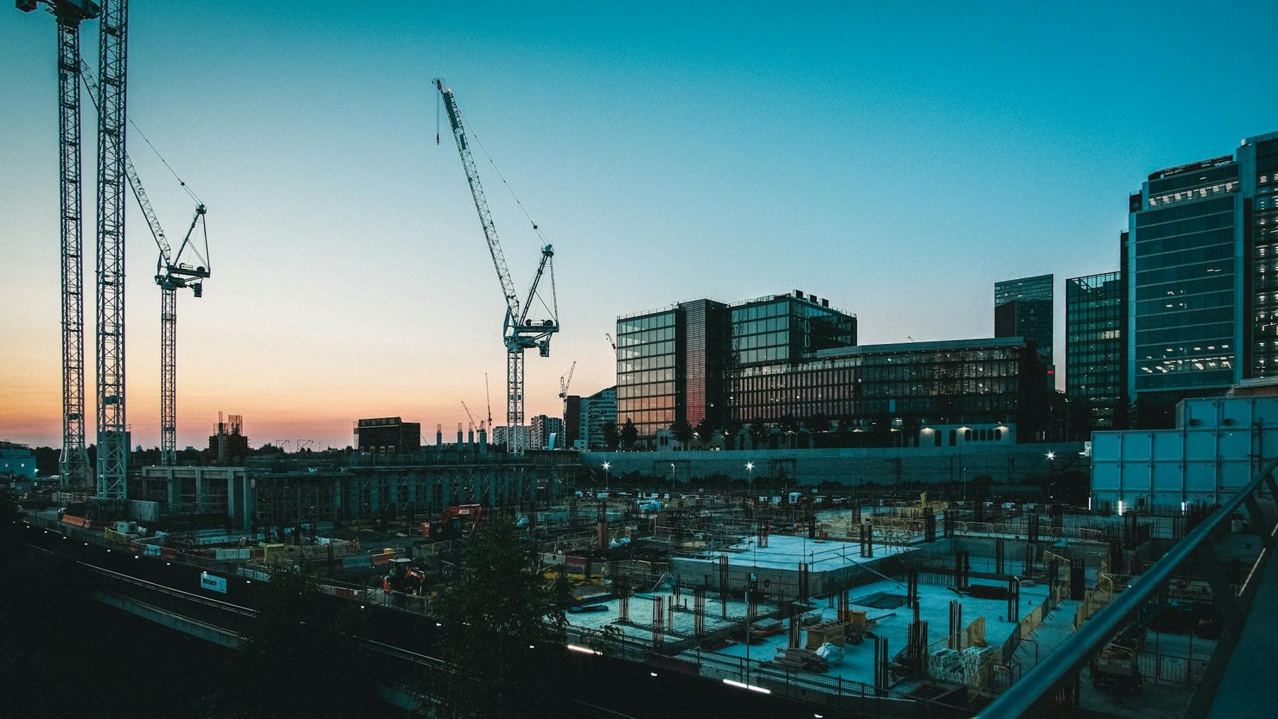 Construction cranes over a building site at sunset