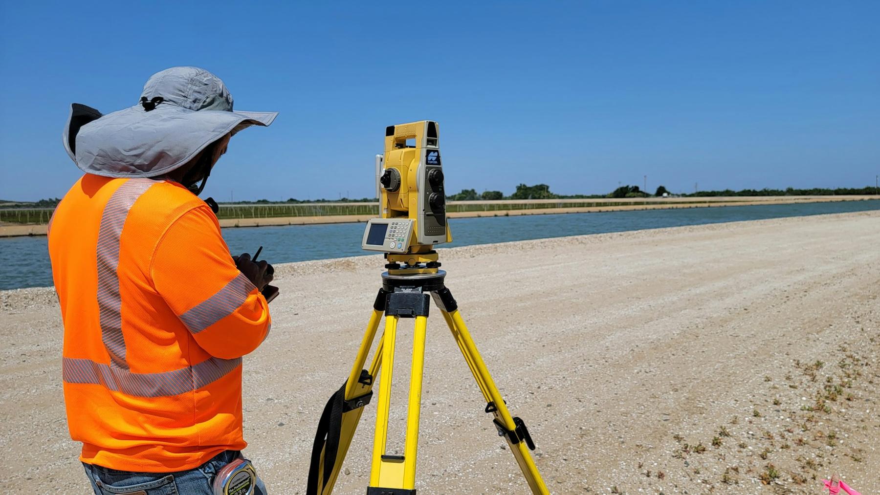 Surveyor in a high-visibility jacket working at a total station