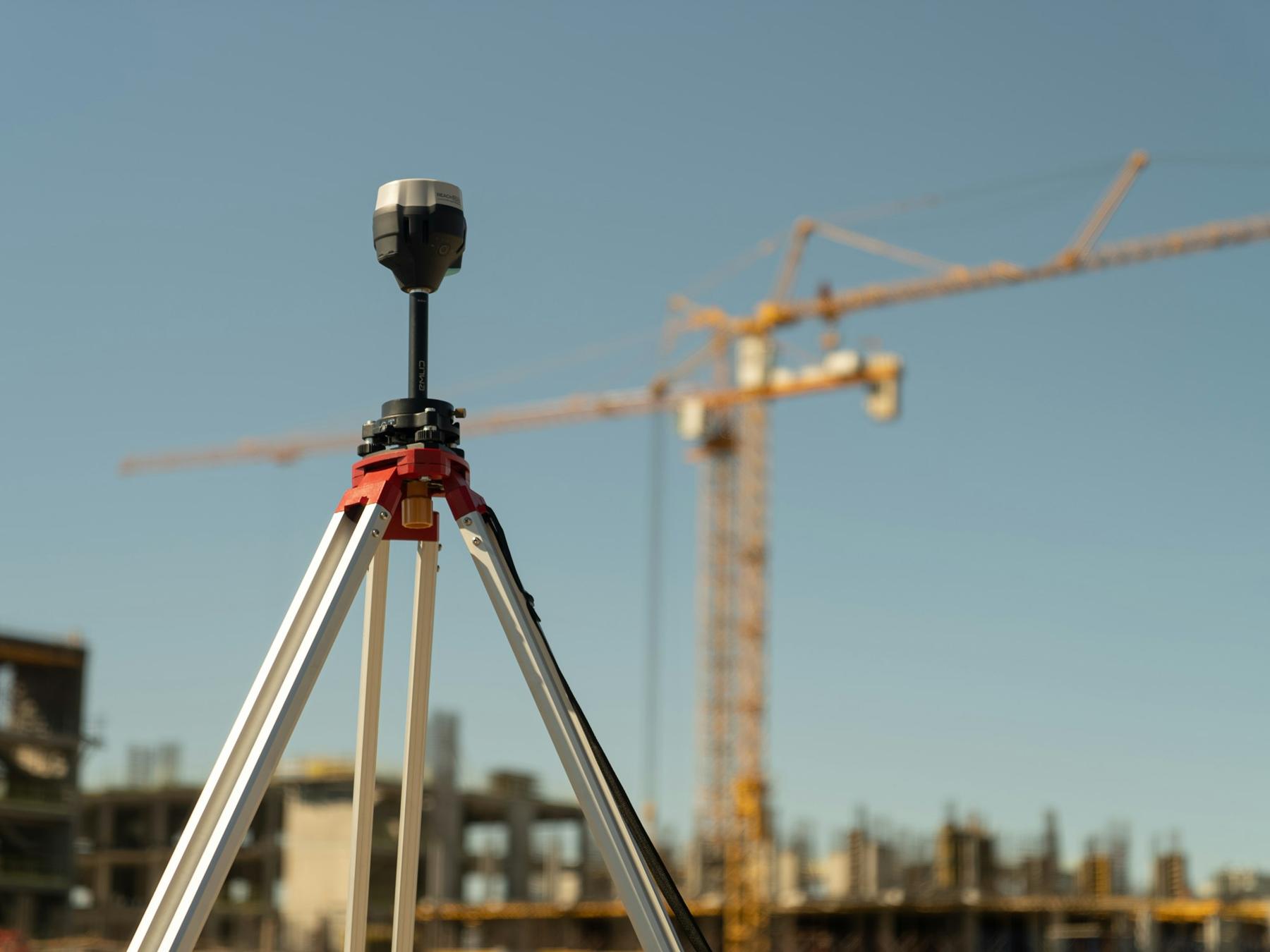 Survey instrument on a tripod in front of a construction site